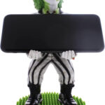 Just in time for the new Beetlejuice film, the ghost with the most is back in action! This time, he's not just causing trouble in the afterlife but is ready to bring his quirky energy to your gaming setup with the officially licensed Beetlejuice Cable Guy Phone & Gaming Controller Stand. Styled after his unmistakable look, this stand is designed to hold your smartphone, remote control, or gaming controller with a mischievous twist. A video game controller with a green and white garmentDescription automatically generated For those who remember the classic 1988 Beetlejuice film, you'll know that this trickster ghost, with his grisly green hair, iconic black-and-white striped suit, and sandworm-stomping boots, is a "professional" in wreaking havoc. Now, thanks to this unique accessory, you can channel that chaotic energy straight to your gaming station. Perfect for die-hard fans of both the original and the upcoming film, this stand blends nostalgia with modern-day practicality. A toy in a boxDescription automatically generated Product Features: Universal Compatibility: Whether you're gaming on the PlayStation 5 DualSense, Xbox Series S/X, or checking your iPhone. Stunning Design: Standing approximately 8.5" tall, Beetlejuice holds your devices with his usual unkempt, grisly charm. It's the perfect blend of fun and function, making it a great gift for fans of the franchise. Officially Licensed: Styled directly from the original Beetlejuice design by ExgPro, it is officially licensed by Warner Brothers, guaranteeing quality and authenticity. The Perfect Gift for Any Beetlejuice Fan Beetlejuice has always been a character who brings a sense of fun, and this stand is no exception. Whether you're a long-time fan of the original Tim Burton film or excited for the new Beetlejuice movie, this accessory is sure to add some mischievous flair to your home. So, why settle for an ordinary phone or controller holder when you can have a trickster ghost on standby? Bring Beetlejuice home today and let him haunt your gaming setup in style! The ExgPro Beetlejuice Cable Guys costs £29.99 from HMV