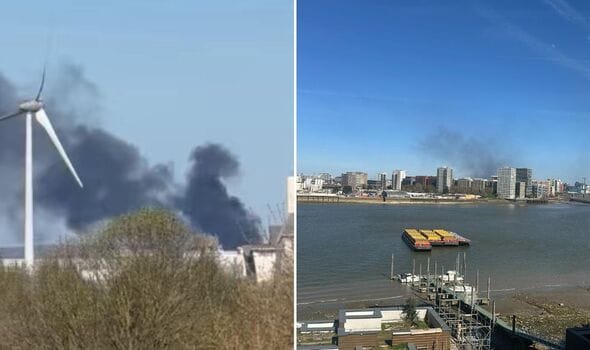 Huge plume of smoke and ash rises dramatically into the clear blue afternoon sky outside